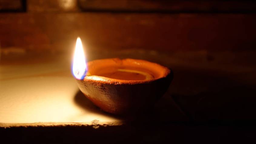 A lit clay diya on a windowsill during Diwali