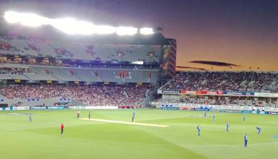 Eden Park in Auckland under floodlights at dusk during a cricket match