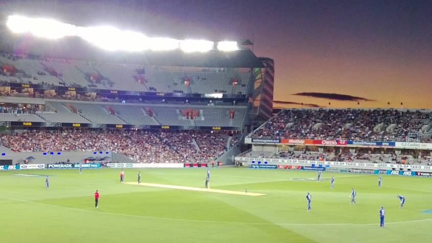 Eden Park in Auckland under floodlights at dusk during a cricket match