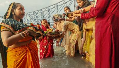 Devotees offering arghya to the setting sun at a river ghat during Chhath Puja