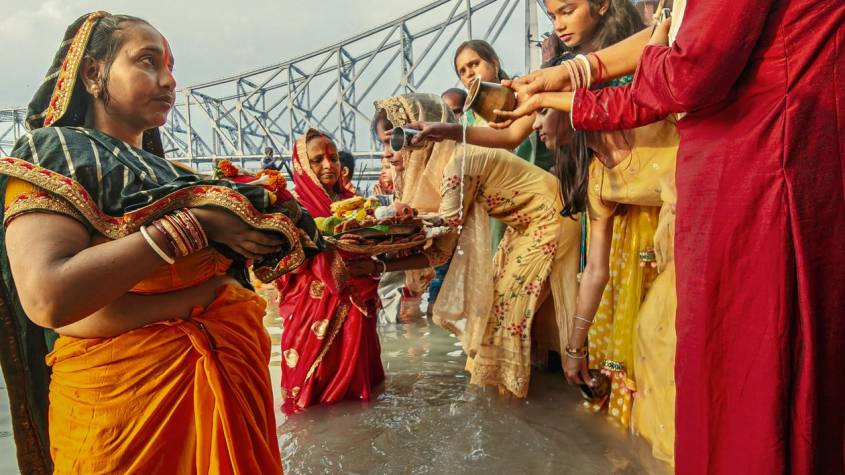 Devotees offering arghya to the setting sun at a river ghat during Chhath Puja